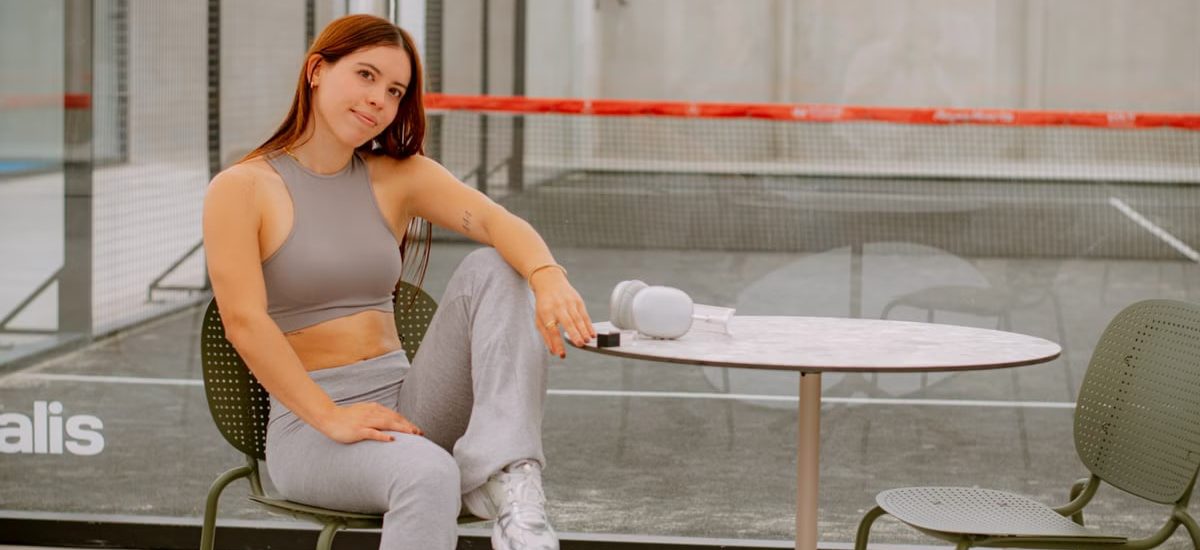 Casual portrait of a young woman sitting at a table beside a padel court in Puebla.